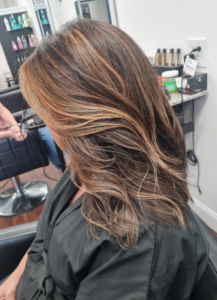 Woman with freshly styled brown hair with blonde highlights in a salon.