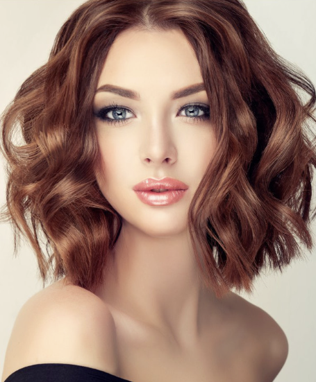 Portrait of a woman with wavy brown hair and striking blue eyes.