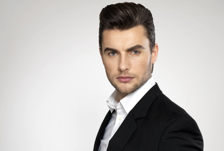 Confident man in a black suit against a white background.