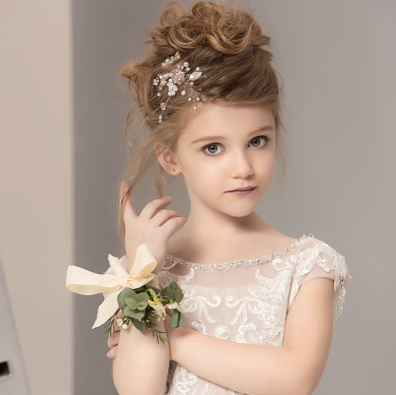 Young girl in a delicate white dress with floral hair accessories and a corsage.